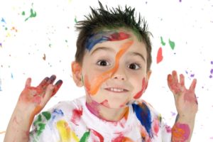 Adorable 3 year old boy covered in bright paint.